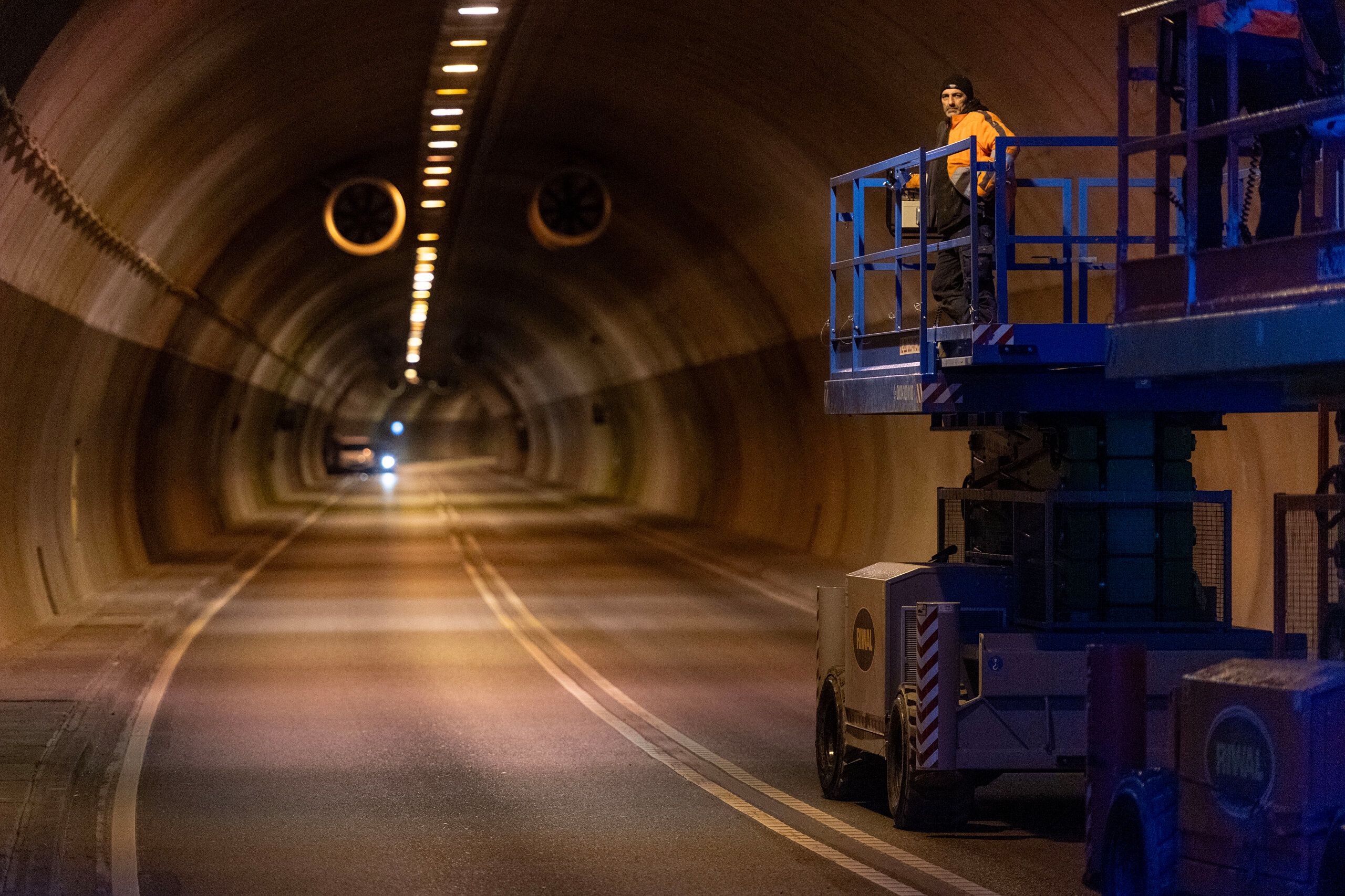 Im Schemelsbergtunnel steht ein Arbeiter auf einem Baufahrzeug. 