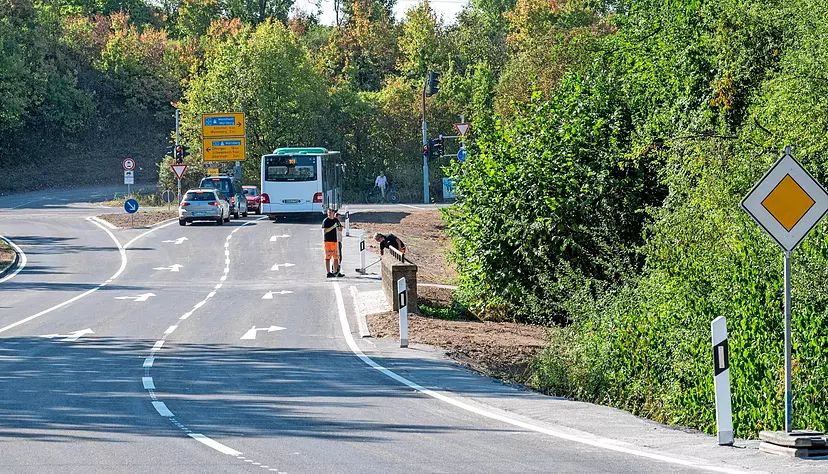 Arbeiter kehren an der Kreisstraße am Weissenhof-Knoten Dreck von der Straße.