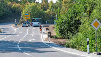 Arbeiter kehren an der Kreisstraße am Weissenhof-Knoten Dreck von der Straße.